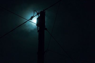 Low angle view of silhouette electricity pylon at night