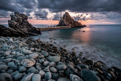 Rocks on shore at beach against sky