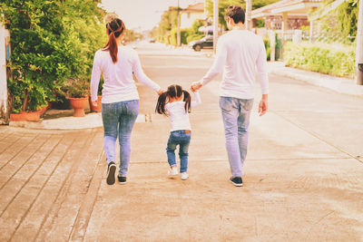 Rear view of family walking on footpath