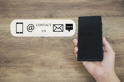 Cropped hand of person using mobile phone on table