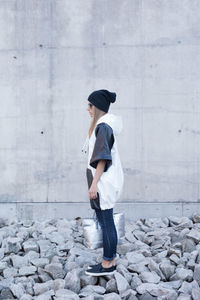 Full length of young woman standing against wall