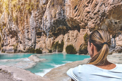 Rear view of woman sitting on rock