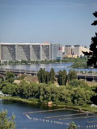 Buildings by river against sky
