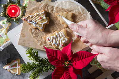Female hands decorate shortbread christmas cookies with icing,