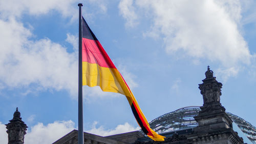 Low angle view of flag statue in city against sky