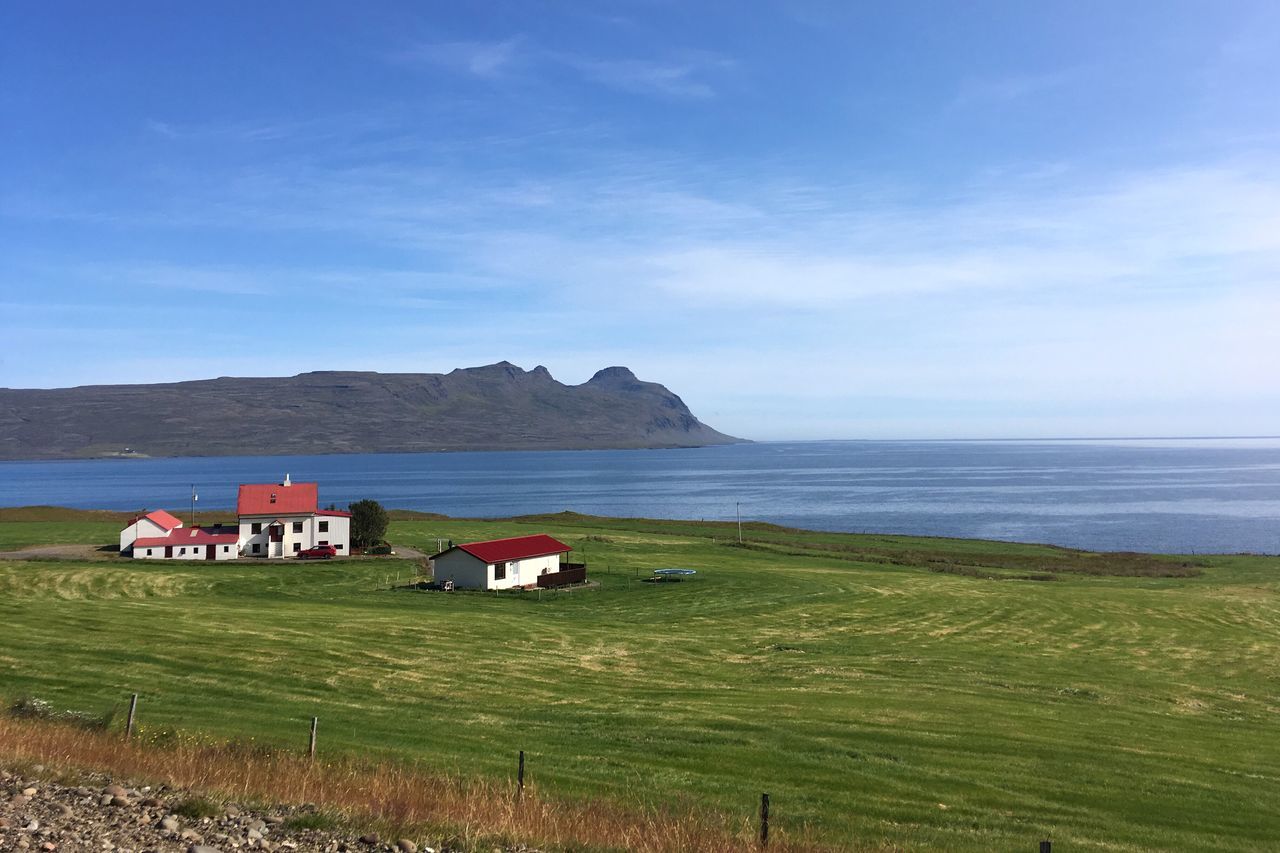 nature, scenics, sea, grass, sky, day, no people, tranquil scene, landscape, outdoors, horizon over water, tranquility, beauty in nature, built structure, blue, mountain, beach, water, architecture, building exterior, tree