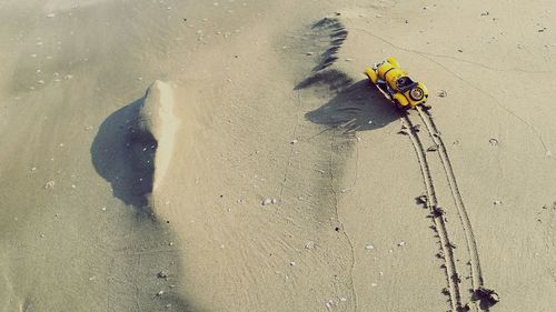 High angle view of toy car with tire tracks on sand at beach