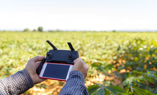 Midsection of man using mobile phone on field