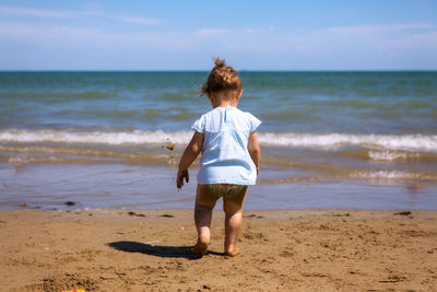 Rear view of baby girl walking at beach