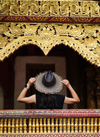 Rear view of woman wearing hat against building
