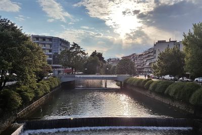 River by buildings in city against sky