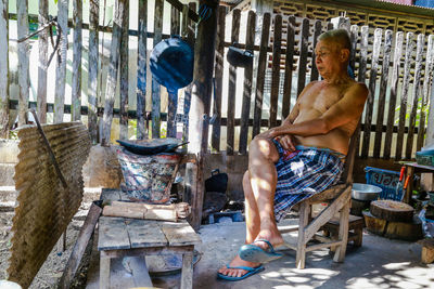 Full length of shirtless man sitting on floor