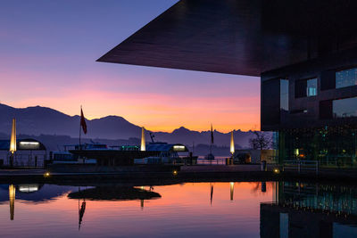 Scenic view of lake by houses against sky at sunrise