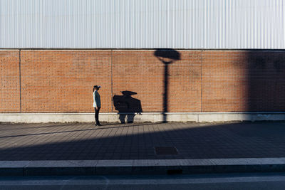 Businesswoman with vr goggles by wall on footpath