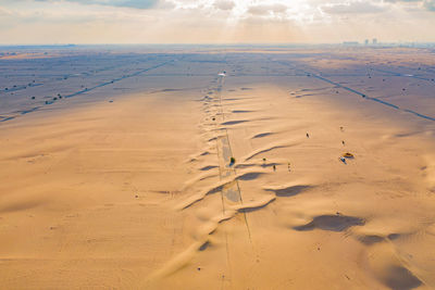 Scenic view of sand dunes at beach against sky