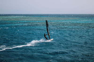 Man surfing in sea against sky