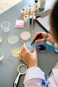 Unrecognizable female chemist examining blue glitter in facial cream sample on laboratory