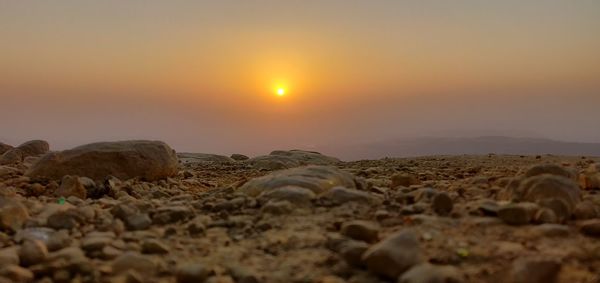 Surface level of rocks on land against sky during sunset