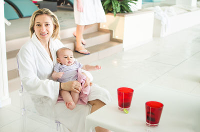 Mom in a spa with newbown baby wear white bathrobe drink tisane