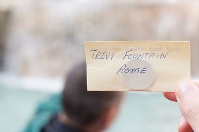 Close-up of hand holding paper with text