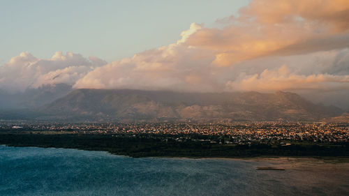 Aerial view of city and mountains against sky during sunset