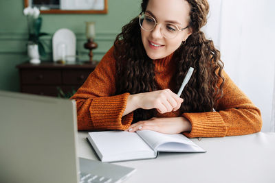 Young woman using mobile phone while sitting at home