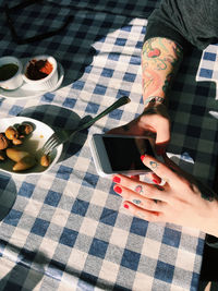 Cropped image of person using smart phone at sidewalk cafe