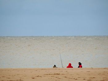 People enjoying at beach against clear sky