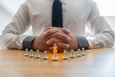 Midsection of man with chess pieces on table