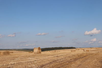 Hay bales on field against sky