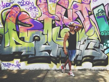 Full length portrait of young man standing against graffiti