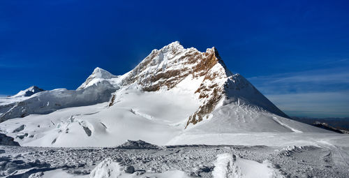 Scenic view of snowcapped mountain against blue sky