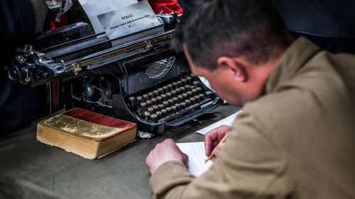 Side view of mature man writing while sitting at office