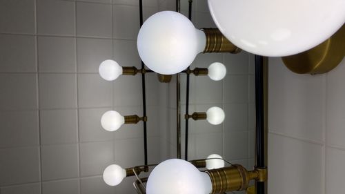 Low angle view of illuminated pendant lights hanging on ceiling at home