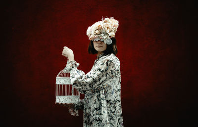 Portrait of woman holding flower against gray background