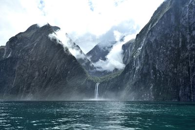 Panoramic view of sea in front of mountains against sky