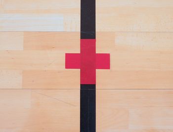 Red cross, playground corner. worn out wooden floor of sports hall with colorful marking lines