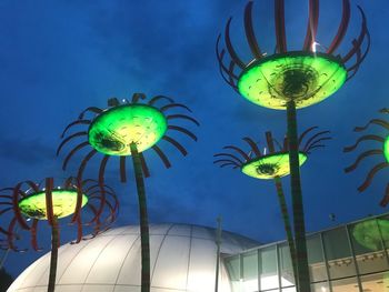 Low angle view of illuminated lighting equipment hanging against blue sky