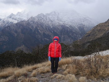 Portrait of mid adult woman in warm clothing standing on mountain against sky