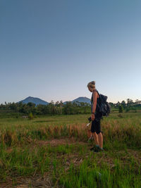 Rear view of woman standing on field against clear sky