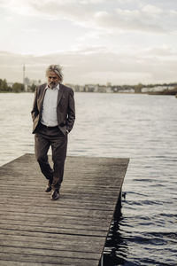 Senior man walking on jetty at a lake