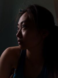 Close-up portrait of a young woman in darkroom