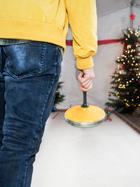 Midsection of man holding umbrella standing by christmas tree