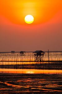 Silhouette bridge over sea against sky during sunset