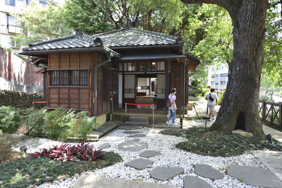 Man standing by house against trees and plants