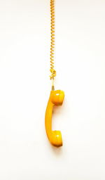 High angle view of yellow bell hanging on white background