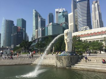 Statue by fountain in city against clear sky