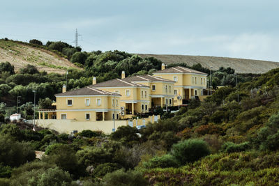 Houses by trees and buildings against sky