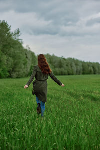 Rear view of woman standing on field against sky