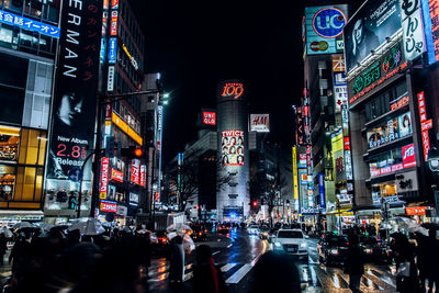 Crowd and cars on road in city at night during rainy season